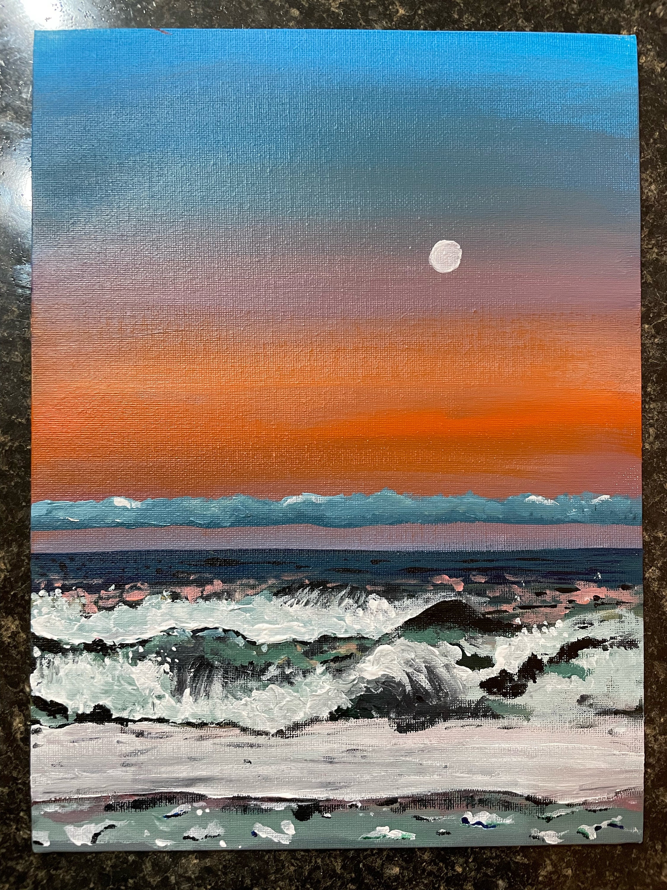 Orange, violet and blue light stretches across the shore as waves roll in beneath the sunset.