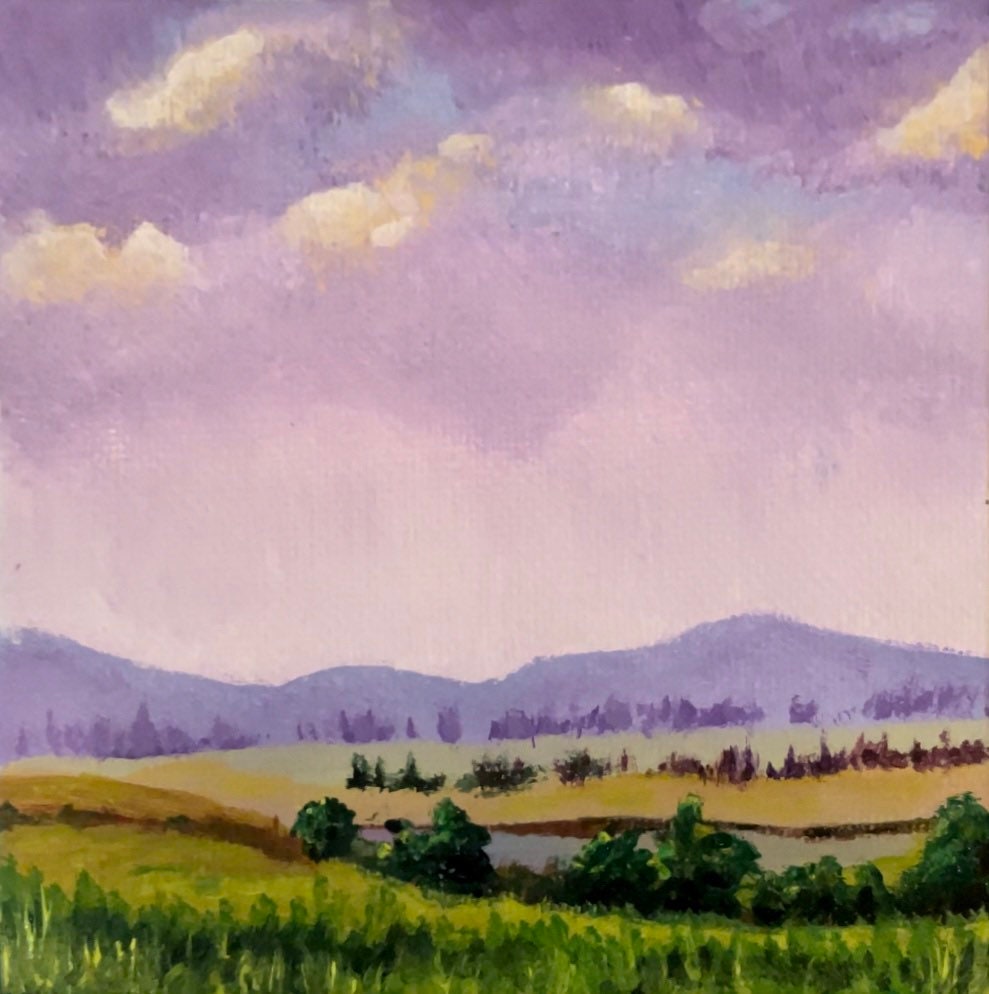 A miniature landscape of purple mountains and open farmland. Big color on a small canvas.