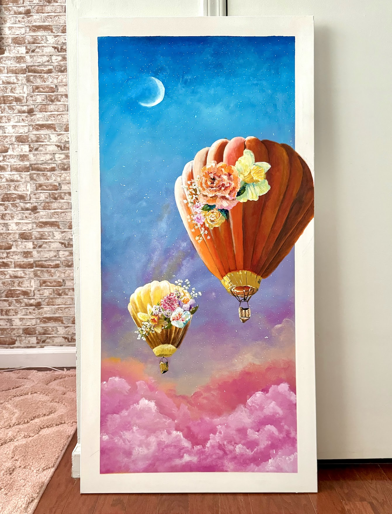 Orange and golden hot-air balloons decorated with flowers float above pink clouds beneath a crescent moon.